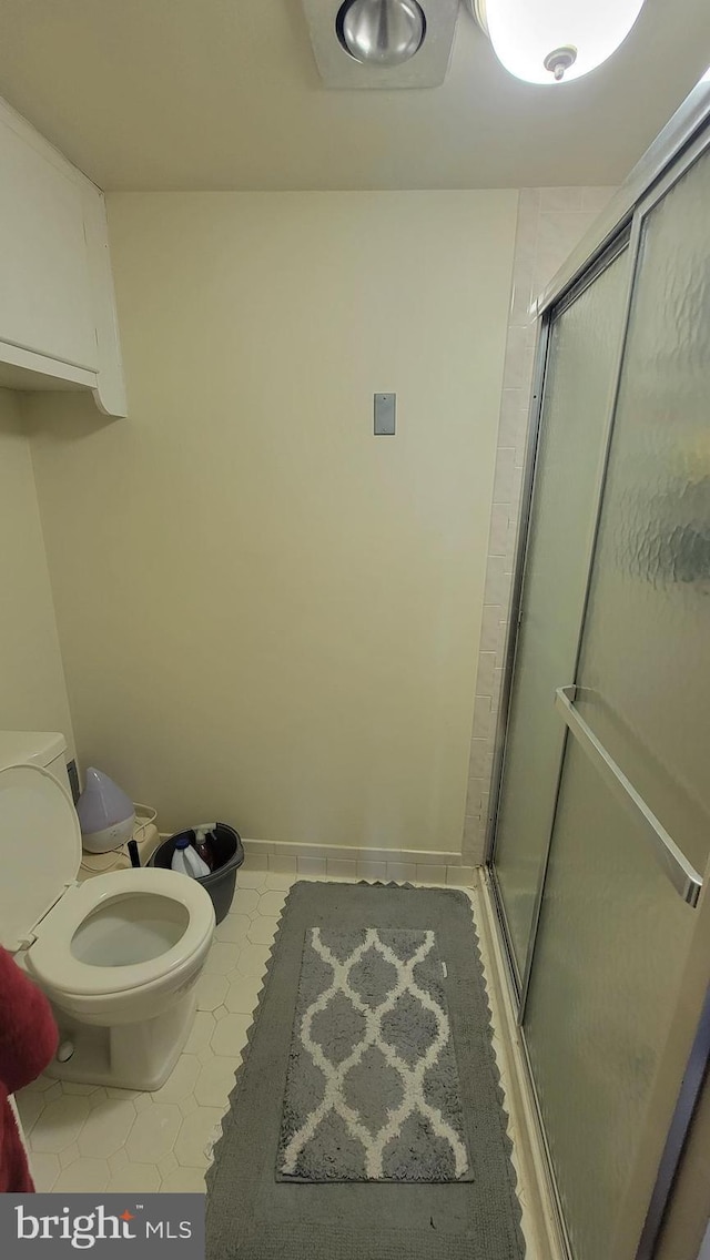 full bath featuring a wall mounted air conditioner, baseboards, toilet, and a stall shower