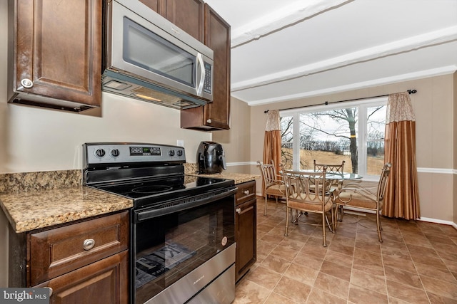 kitchen with light stone counters, dark brown cabinets, appliances with stainless steel finishes, and baseboards