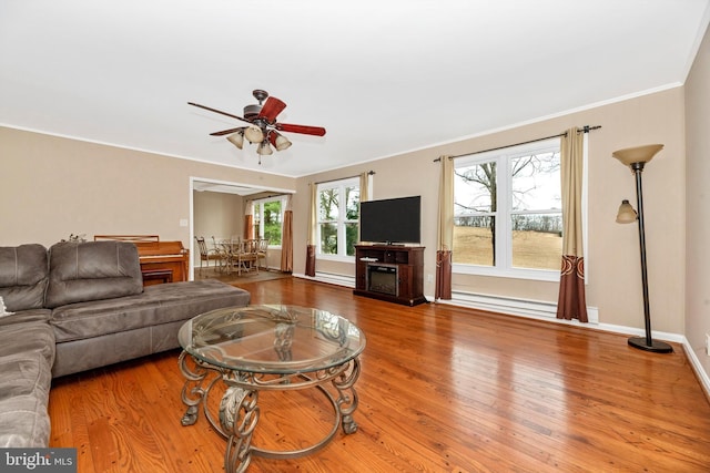 living area featuring baseboards, a ceiling fan, wood finished floors, and a fireplace