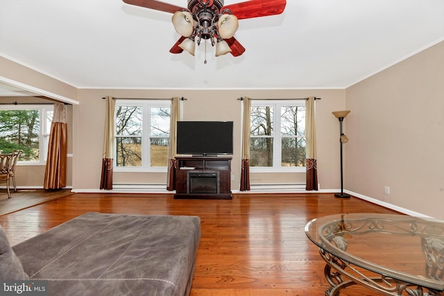 living room with ornamental molding, a fireplace, baseboards, and wood finished floors