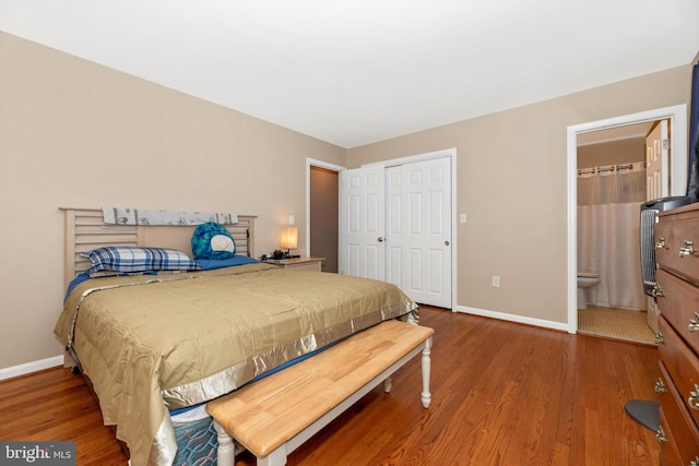 bedroom featuring ensuite bathroom, wood finished floors, baseboards, and a closet