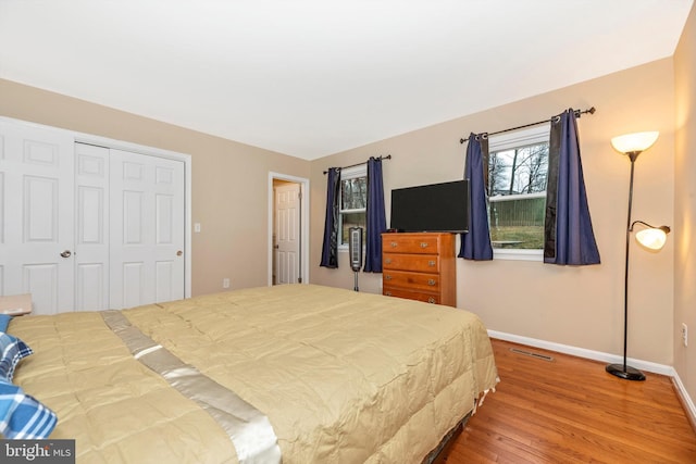 bedroom with wood finished floors, baseboards, and a closet