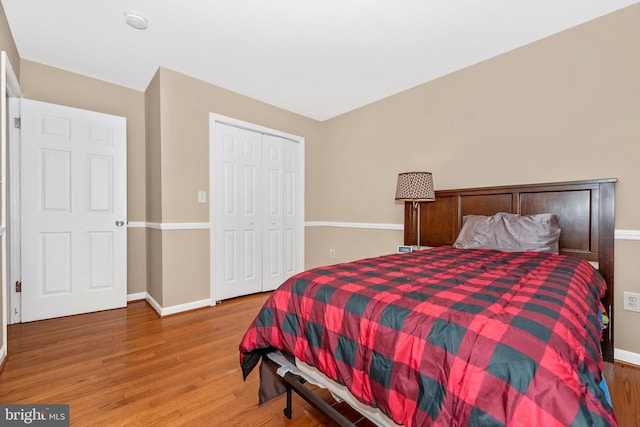 bedroom featuring wood finished floors, baseboards, and a closet