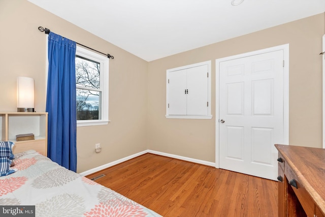 bedroom with visible vents, light wood-type flooring, and baseboards