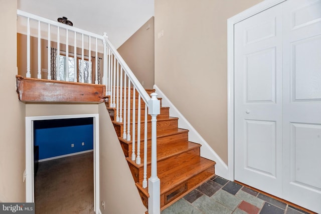 staircase with stone finish floor and baseboards