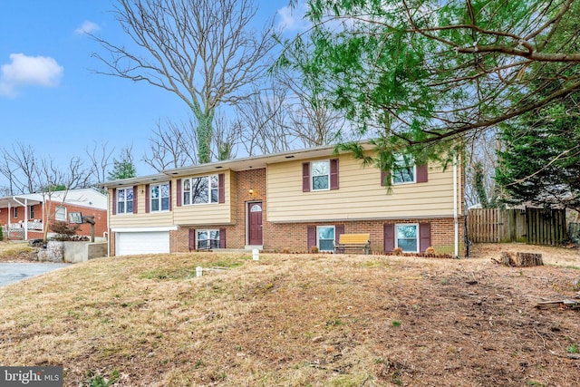 bi-level home with brick siding, an attached garage, and fence