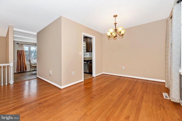 unfurnished dining area with visible vents, baseboards, light wood-style floors, and an inviting chandelier