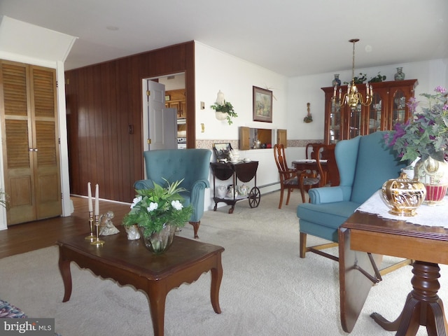 carpeted living room featuring a notable chandelier and wood walls