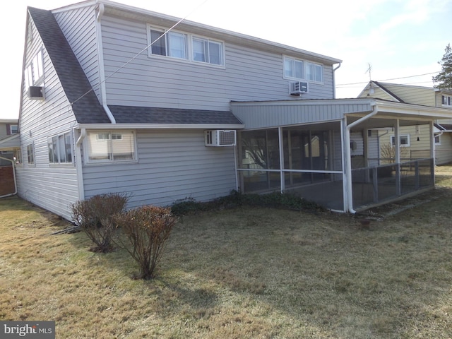 back of house featuring a sunroom, a lawn, a shingled roof, and a wall mounted AC