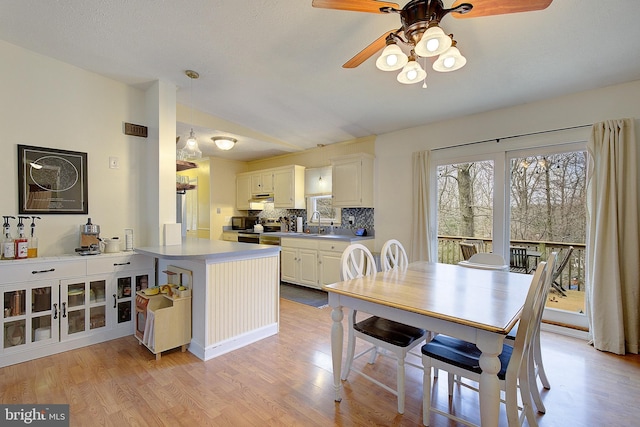 dining room with vaulted ceiling, a ceiling fan, and light wood-style floors