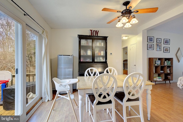 dining area featuring ceiling fan, light wood-style flooring, and baseboards