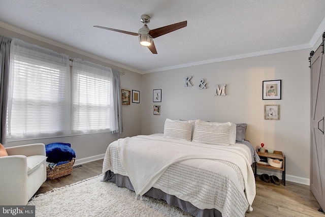 bedroom featuring light wood finished floors, a barn door, and a textured ceiling