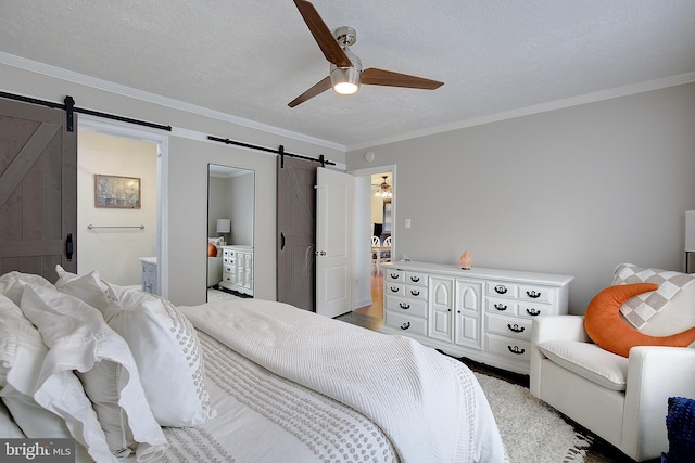 bedroom with a barn door, a ceiling fan, connected bathroom, ornamental molding, and a textured ceiling