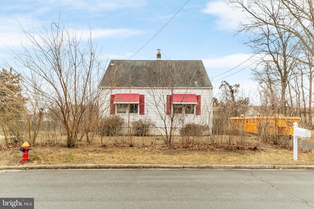 view of property exterior with a shingled roof and a chimney