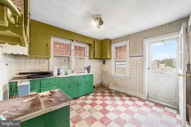 kitchen with green cabinets, light floors, baseboards, and wallpapered walls