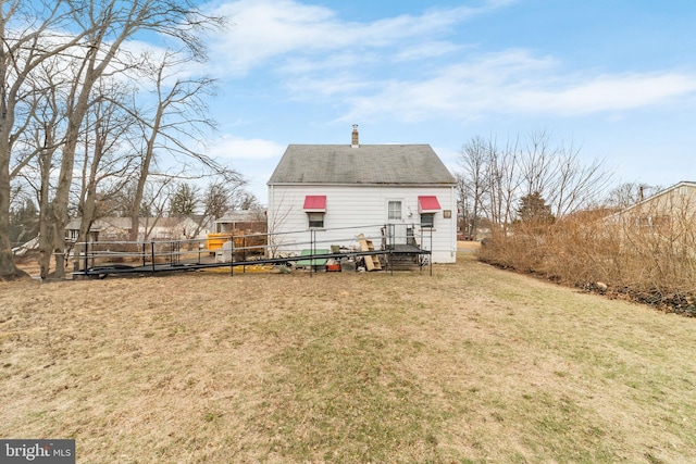 back of property featuring a lawn, a chimney, and fence