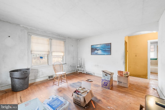 living area featuring arched walkways, visible vents, and wood finished floors