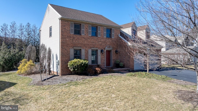 view of front facade featuring an attached garage, brick siding, driveway, roof with shingles, and a front lawn