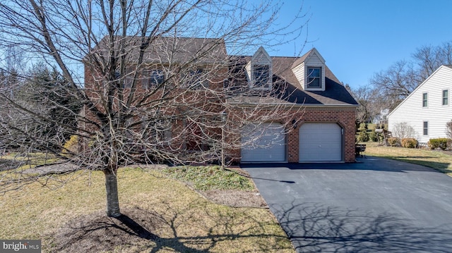 cape cod-style house with a garage, brick siding, a front yard, and aphalt driveway