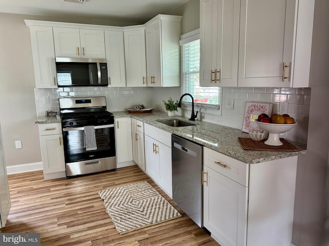 kitchen featuring a sink, stainless steel appliances, light wood-style flooring, and white cabinetry