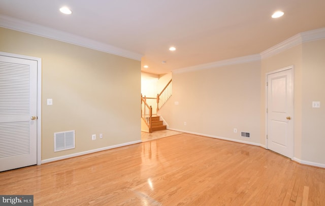 empty room with light wood finished floors, stairway, visible vents, and crown molding