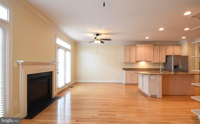 kitchen featuring dark stone countertops, light wood finished floors, stainless steel refrigerator with ice dispenser, and crown molding