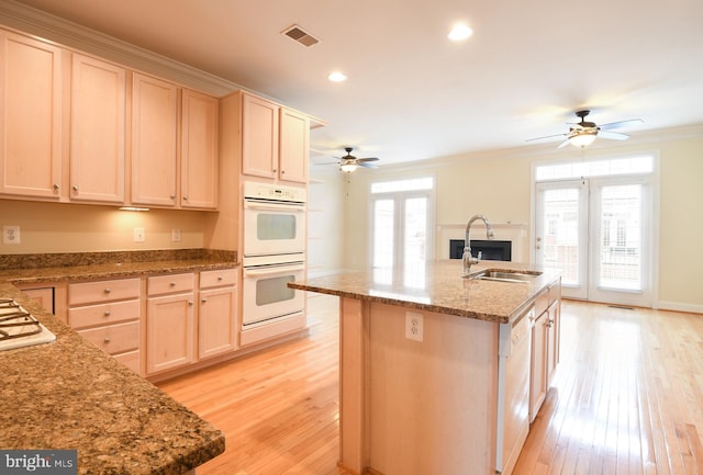 kitchen with crown molding, visible vents, light brown cabinetry, a sink, and white appliances