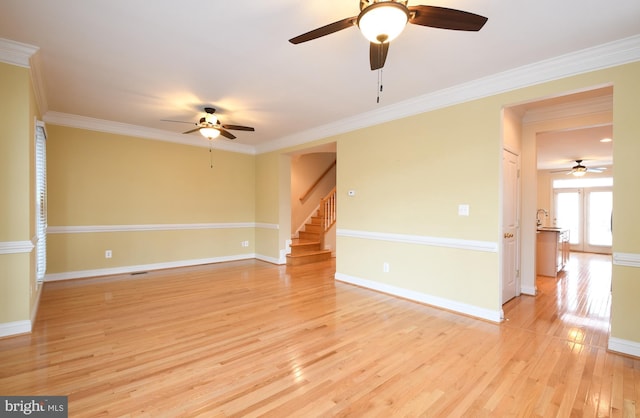 unfurnished room with ornamental molding, stairway, and light wood-style flooring