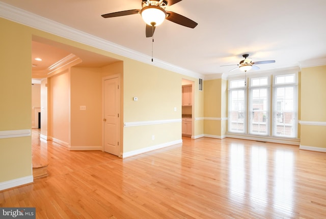 spare room with baseboards, light wood-type flooring, and crown molding