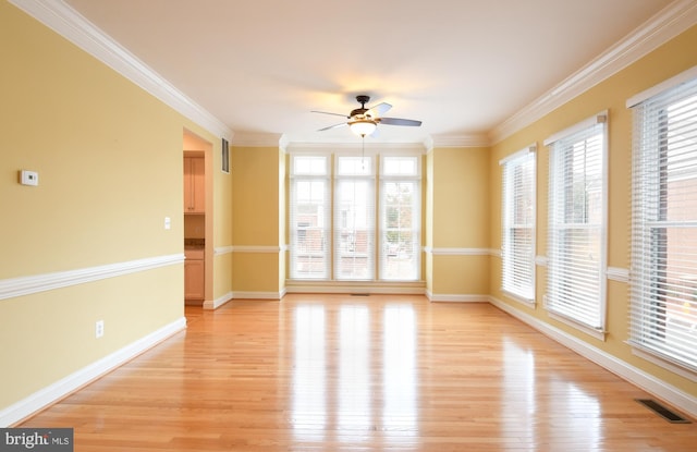 unfurnished room featuring crown molding, light wood finished floors, visible vents, a ceiling fan, and baseboards