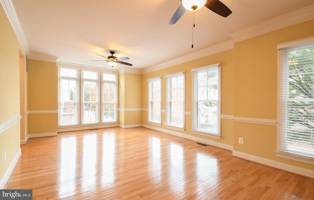 spare room featuring crown molding, visible vents, light wood-style flooring, a ceiling fan, and baseboards