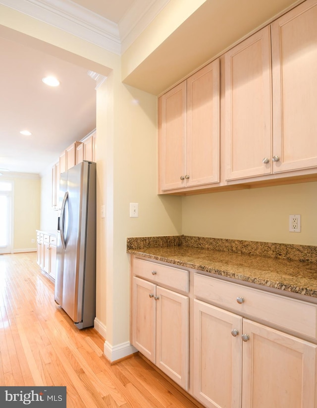 kitchen with light stone counters, light wood-style flooring, baseboards, stainless steel fridge with ice dispenser, and crown molding