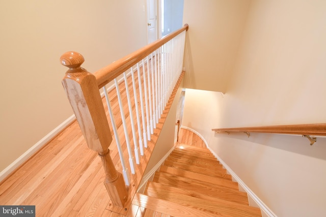 stairs with a towering ceiling, baseboards, and wood finished floors