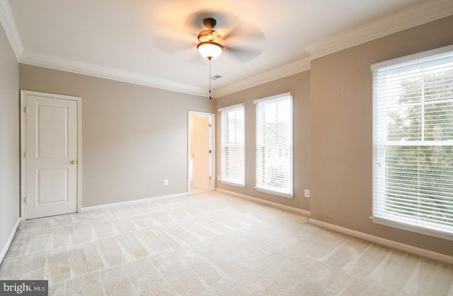 spare room featuring a wealth of natural light, baseboards, crown molding, and light colored carpet