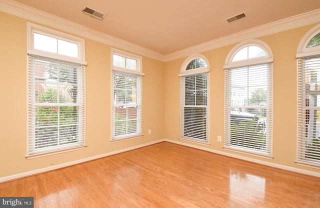 unfurnished room featuring wood finished floors, visible vents, and crown molding