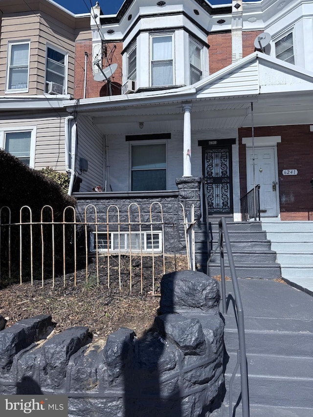 exterior space with covered porch, brick siding, and fence