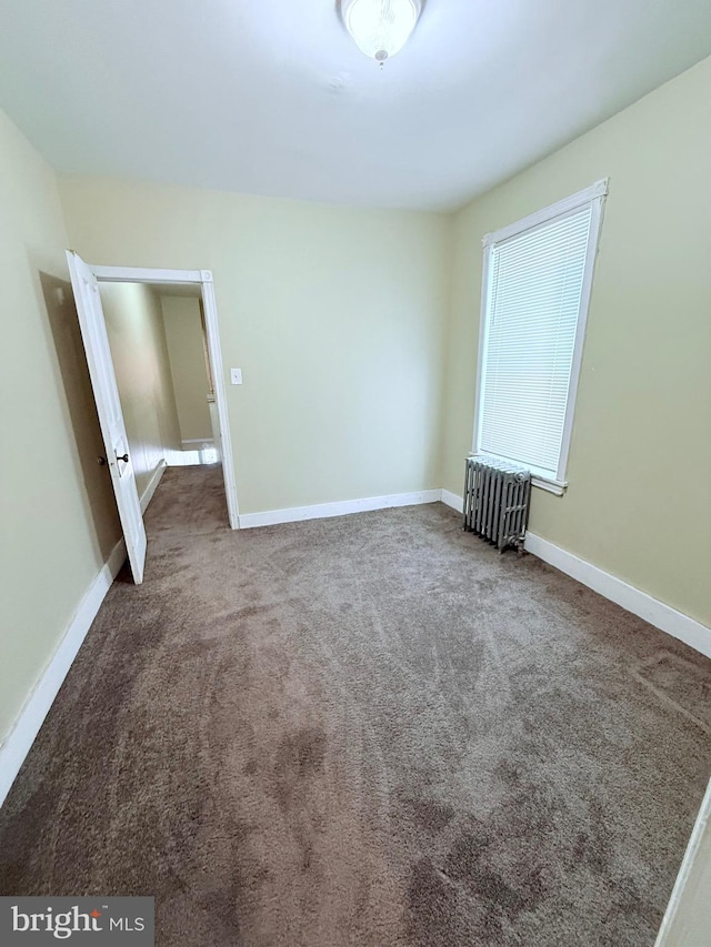 unfurnished bedroom featuring radiator heating unit, carpet flooring, and baseboards