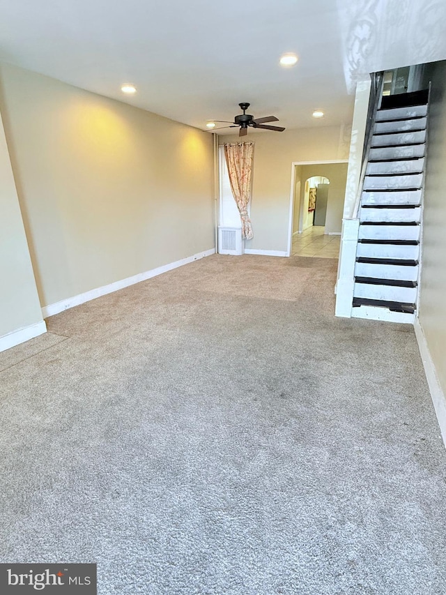 unfurnished living room with carpet, visible vents, arched walkways, and baseboards