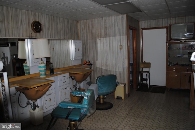 kitchen featuring carpet, a paneled ceiling, and wooden walls