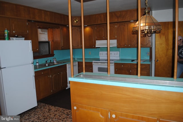 kitchen with white appliances, wooden walls, brown cabinetry, a sink, and exhaust hood