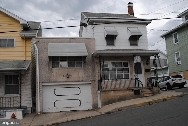 view of front facade with a garage, a chimney, a porch, and brick siding