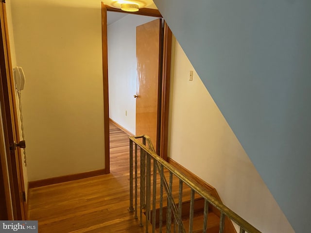 hallway with baseboards, wood finished floors, and an upstairs landing