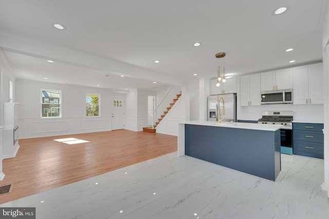 kitchen with open floor plan, light countertops, recessed lighting, appliances with stainless steel finishes, and a decorative wall