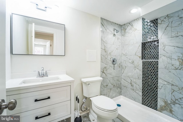 full bathroom with a tile shower, toilet, and vanity