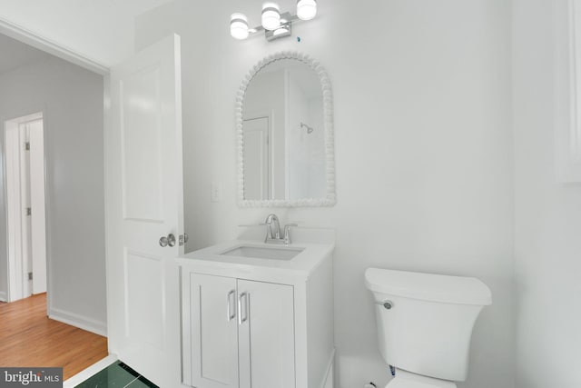 bathroom with toilet, vanity, baseboards, and wood finished floors