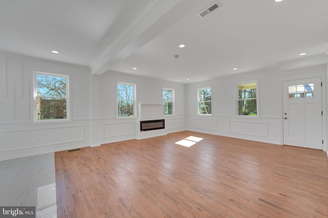 unfurnished living room with visible vents, light wood-style floors, and a glass covered fireplace