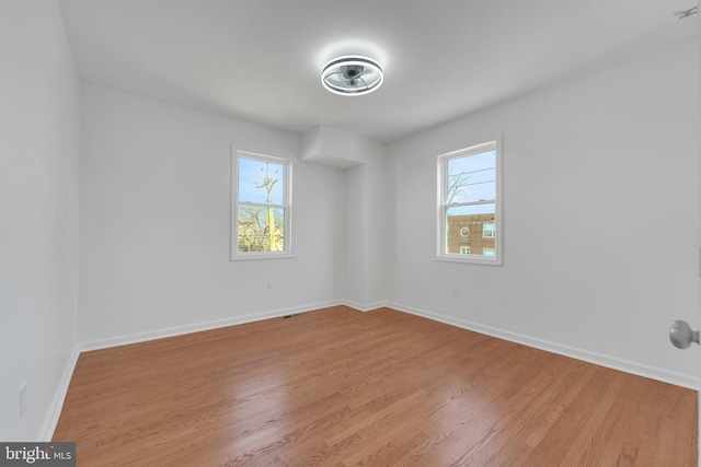 spare room with plenty of natural light, baseboards, and light wood-style floors