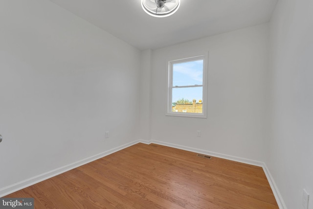 unfurnished room with wood finished floors, visible vents, and baseboards