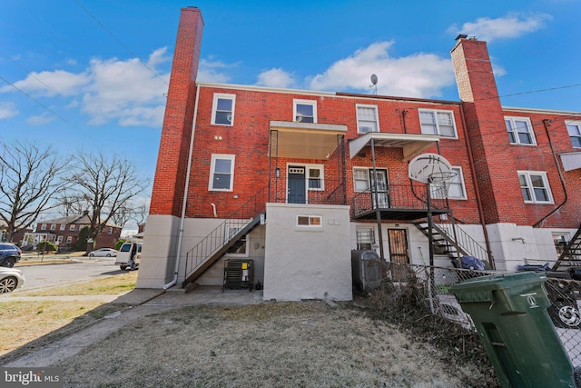 rear view of house with central air condition unit, stairway, and brick siding