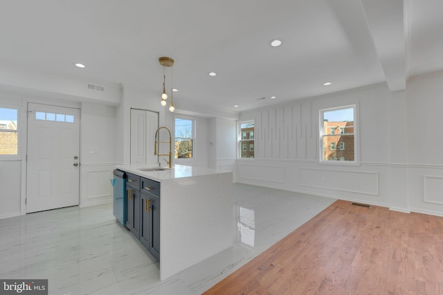 kitchen featuring visible vents, marble finish floor, a sink, stainless steel dishwasher, and a decorative wall